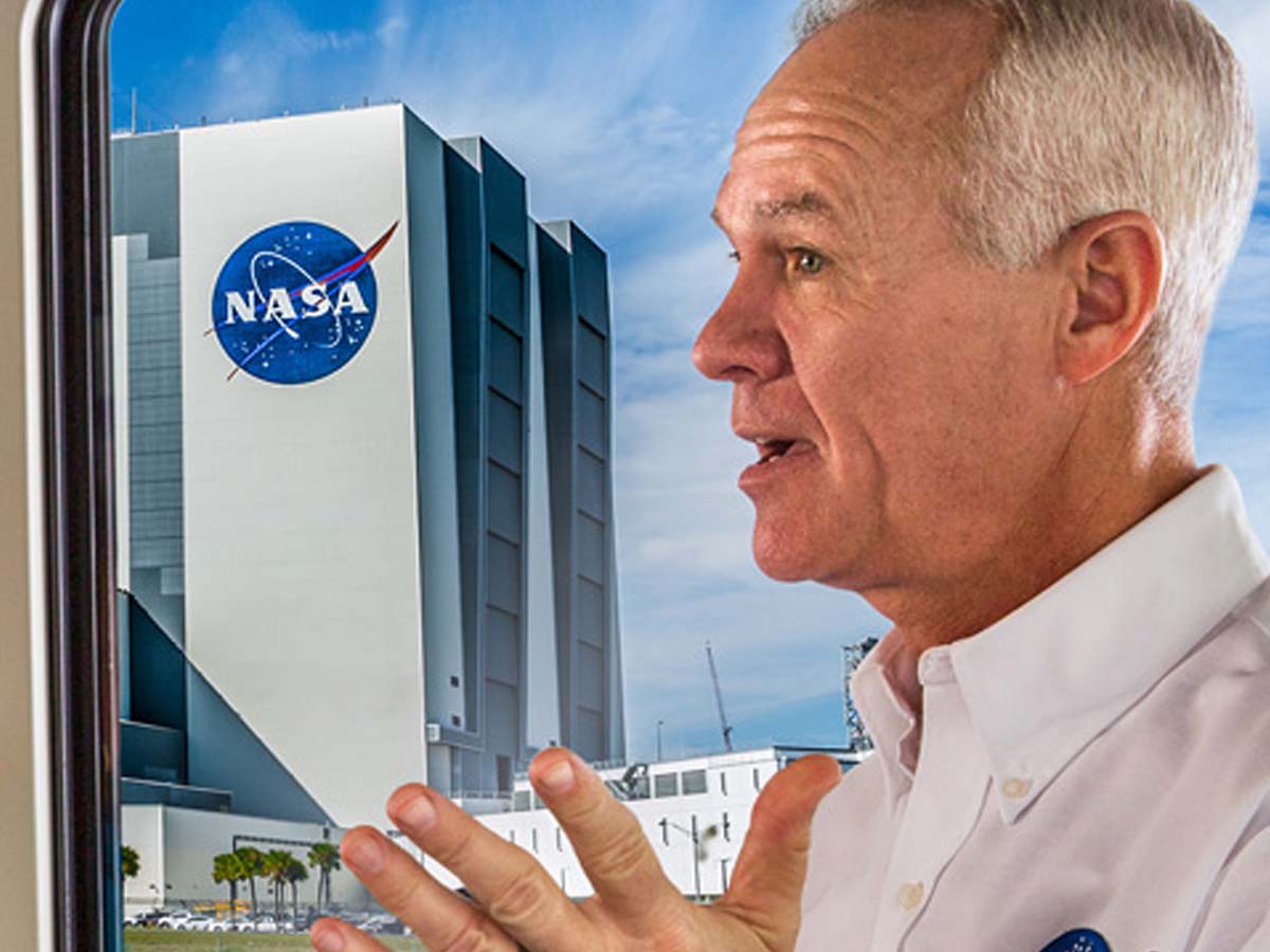 Tour guide speaks to visitors on a bus while passing by NASA buildings during the Kennedy Space Center Bus Tour.