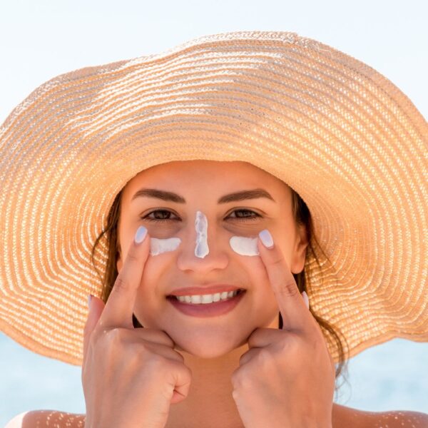 Woman smiling while applying sunscreen