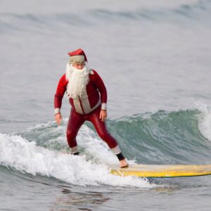man dressed as Santa surfing on yellow surfboard